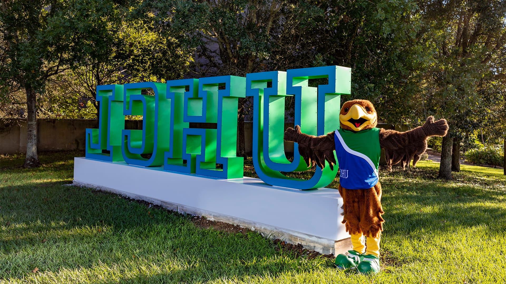 Hunter Hawk standing in front of the UHCL letters